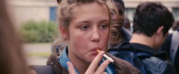 Movie still from “Blue Is the Warmest Colour” (2013), directed by Abdellatif Kechiche – A young woman is smoking a cigarette outside; Close Up shot, Over the shoulder angle