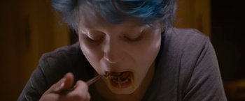 Movie still from “Blue Is the Warmest Colour” (2013), directed by Abdellatif Kechiche – A person with blue hair eating food with chopsticks; Extreme Close Up shot, Overhead angle