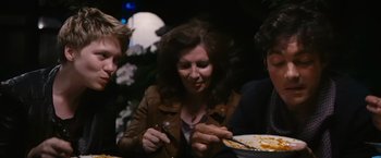 Movie still from “Blue Is the Warmest Colour” (2013), directed by Abdellatif Kechiche – A woman sitting at a dinner table with a plate of food; Medium shot, Over the shoulder angle