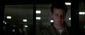 Movie still from “Blue Thunder” (1983), directed by John Badham – A young man is looking at the camera while standing in front of a window; Close Up shot, Low angle