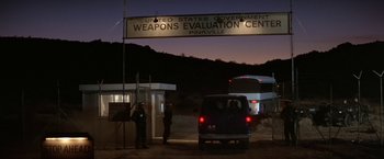 Movie still from “Blue Thunder” (1983), directed by John Badham – A car parked in front of a building with a sign above it; Extreme Wide shot, High angle