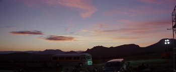 Movie still from “Blue Thunder” (1983), directed by John Badham – A group of people sitting in front of two buses; Extreme Wide shot, Low angle