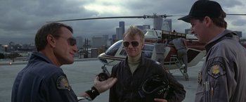 Movie still from “Blue Thunder” (1983), directed by John Badham – A man is being interviewed in front of a helicopter; Medium shot, Low angle