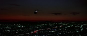 Movie still from “Blue Thunder” (1983), directed by John Badham – A helicopter flying over a city at night; Extreme Wide shot, High angle