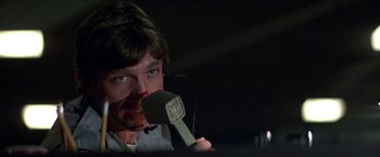 Movie still from “Blue Thunder” (1983), directed by John Badham – A man holding a microphone up to his mouth; Close Up shot, Low angle