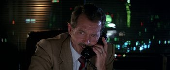 Movie still from “Blue Thunder” (1983), directed by John Badham – An older man talking on a phone while wearing a suit and tie; Close Up shot, High angle