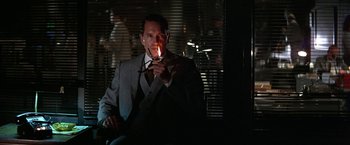 Movie still from “Blue Thunder” (1983), directed by John Badham – A man in a suit holding a lit cigarette; Close Up shot, Low angle