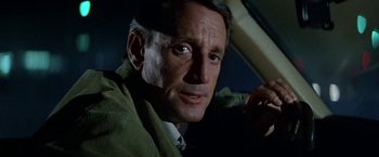 Movie still from “Blue Thunder” (1983), directed by John Badham – A man in a green jacket looking at the camera; Close Up shot, Low angle