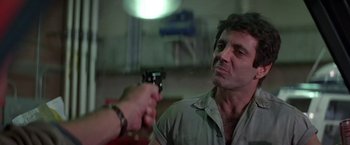 Movie still from “Blue Thunder” (1983), directed by John Badham – A man holding a gun pointed at another man; Close Up shot, Over the shoulder angle