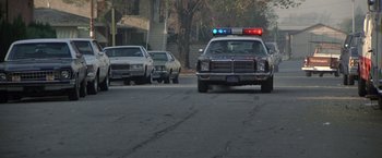 Movie still from “Blue Thunder” (1983), directed by John Badham – A police car is parked on the side of the road; Wide shot, Low angle