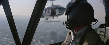 Movie still from “Blue Thunder” (1983), directed by John Badham – A man in a helicopter flying over a city; Close Up shot, Over the shoulder angle