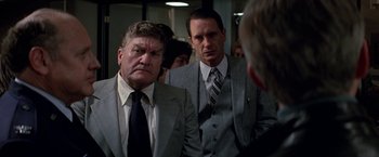Movie still from “Blue Thunder” (1983), directed by John Badham – Two men in suits and ties looking at each other; Medium shot, Over the shoulder angle