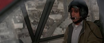 Movie still from “Blue Thunder” (1983), directed by John Badham – A man wearing a helmet looking out of a helicopter window; Medium shot, Over the shoulder angle
