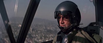 Movie still from “Blue Thunder” (1983), directed by John Badham – A man wearing a helmet is sitting in the cockpit of a helicopter; Close Up shot, Low angle