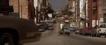 Movie still from “Blue Velvet” (1986), directed by David Lynch – A man riding a skateboard down the middle of a street; Extreme Wide shot, High angle