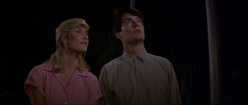 Movie still from “Blue Velvet” (1986), directed by David Lynch – A man and a woman standing next to each other looking up; Medium shot, Low angle
