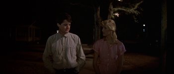 Movie still from “Blue Velvet” (1986), directed by David Lynch – A man and a woman standing next to each other in front of trees; Medium shot, Over the shoulder angle
