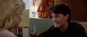 Movie still from “Blue Velvet” (1986), directed by David Lynch – A man sitting at a table with a drink in front of him; Close Up shot, Over the shoulder angle