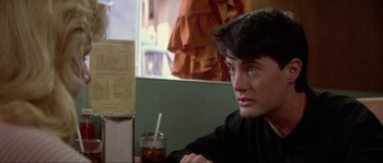 Movie still from “Blue Velvet” (1986), directed by David Lynch – A man sitting at a table with a drink in front of him; Close Up shot, Over the shoulder angle