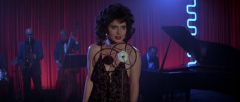 Movie still from “Blue Velvet” (1986), directed by David Lynch – A woman standing in front of a microphone in front of a stage; Medium shot, Over the shoulder angle