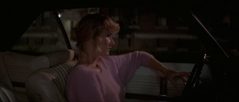 Movie still from “Blue Velvet” (1986), directed by David Lynch – A woman in a pink sweater looking out of a window; Medium shot, Over the shoulder angle