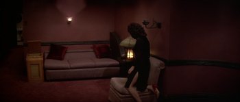 Movie still from “Blue Velvet” (1986), directed by David Lynch – A woman sitting on a chair in a living room; Wide shot, High angle