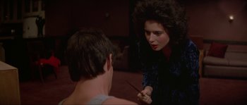 Movie still from “Blue Velvet” (1986), directed by David Lynch – A woman is holding a knife in front of a young man; Medium shot, Over the shoulder angle
