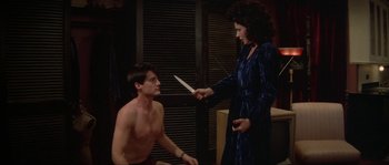 Movie still from “Blue Velvet” (1986), directed by David Lynch – A man and a woman holding a knife in a room; Medium shot, High angle