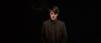 Movie still from “Blue Velvet” (1986), directed by David Lynch – A man in a black jacket and a black tie; Close Up shot, Low angle