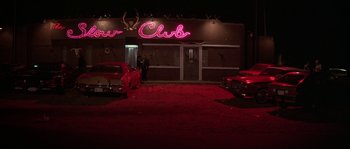 Movie still from “Blue Velvet” (1986), directed by David Lynch – A man standing in front of a red neon sign; Extreme Wide shot, Low angle