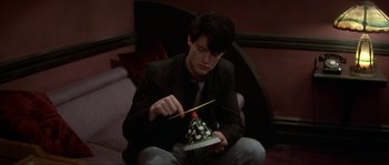 Movie still from “Blue Velvet” (1986), directed by David Lynch – A young man is holding a birthday cake; Medium shot, High angle