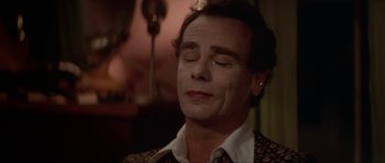 Movie still from “Blue Velvet” (1986), directed by David Lynch – A man with his eyes closed is sitting down; Close Up shot, High angle