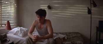 Movie still from “Blue Velvet” (1986), directed by David Lynch – A man sitting on a bed in his underwear; Medium shot, Low angle