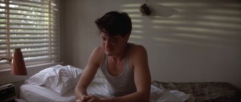 Movie still from “Blue Velvet” (1986), directed by David Lynch – A young man sitting on top of a bed in a room; Close Up shot, High angle