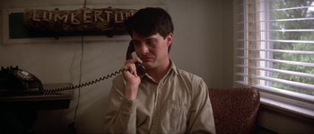 Movie still from “Blue Velvet” (1986), directed by David Lynch – A man sitting on a couch talking on a phone; Close Up shot, Low angle