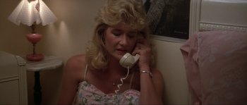 Movie still from “Blue Velvet” (1986), directed by David Lynch – A woman sitting on a wall talking on a phone; Close Up shot, High angle