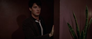Movie still from “Blue Velvet” (1986), directed by David Lynch – A man in a suit leaning against a wall; Close Up shot, Over the shoulder angle