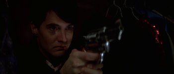 Movie still from “Blue Velvet” (1986), directed by David Lynch – A woman is holding a gun in a dark room; Close Up shot, Low angle