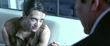Movie still from “Boarding Gate” (2007), directed by Olivier Assayas – A woman is smoking a cigarette while sitting on a couch; Close Up shot, Over the shoulder angle