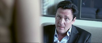 Movie still from “Boarding Gate” (2007), directed by Olivier Assayas – A person wearing a suit and tie; Close Up shot, Over the shoulder angle