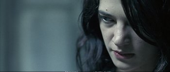 Movie still from “Boarding Gate” (2007), directed by Olivier Assayas – A woman's face in a dark room; Close Up shot, Over the shoulder angle