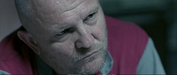 Movie still from “Boarding Gate” (2007), directed by Olivier Assayas – An older man with a beard and mustache looking to his left; Close Up shot, Low angle