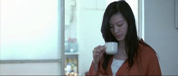 Movie still from “Boarding Gate” (2007), directed by Olivier Assayas – A woman is holding a cup of coffee in her hand; Medium shot, Low angle