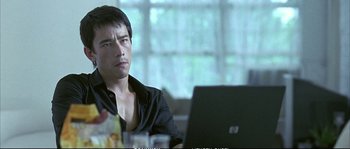 Movie still from “Boarding Gate” (2007), directed by Olivier Assayas – A man sitting in front of a laptop computer; Close Up shot, Over the shoulder angle