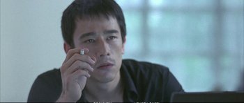 Movie still from “Boarding Gate” (2007), directed by Olivier Assayas – A man holding a cell phone up to his face; Close Up shot, High angle