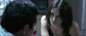 Movie still from “Boarding Gate” (2007), directed by Olivier Assayas – A woman sitting at a table with a glass of red wine; Close Up shot, Over the shoulder angle