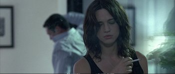 Movie still from “Boarding Gate” (2007), directed by Olivier Assayas – A woman with long dark hair is looking down at her face; Close Up shot, Over the shoulder angle