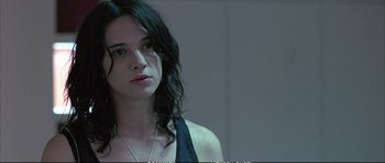 Movie still from “Boarding Gate” (2007), directed by Olivier Assayas – A woman with long black hair is looking at the camera; Close Up shot, Over the shoulder angle