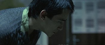 Movie still from “Boarding Gate” (2007), directed by Olivier Assayas – A young man with short black hair is looking down; Close Up shot, Low angle