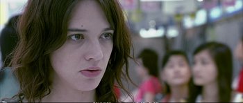 Movie still from “Boarding Gate” (2007), directed by Olivier Assayas – A woman's face in the background; Close Up shot, Over the shoulder angle